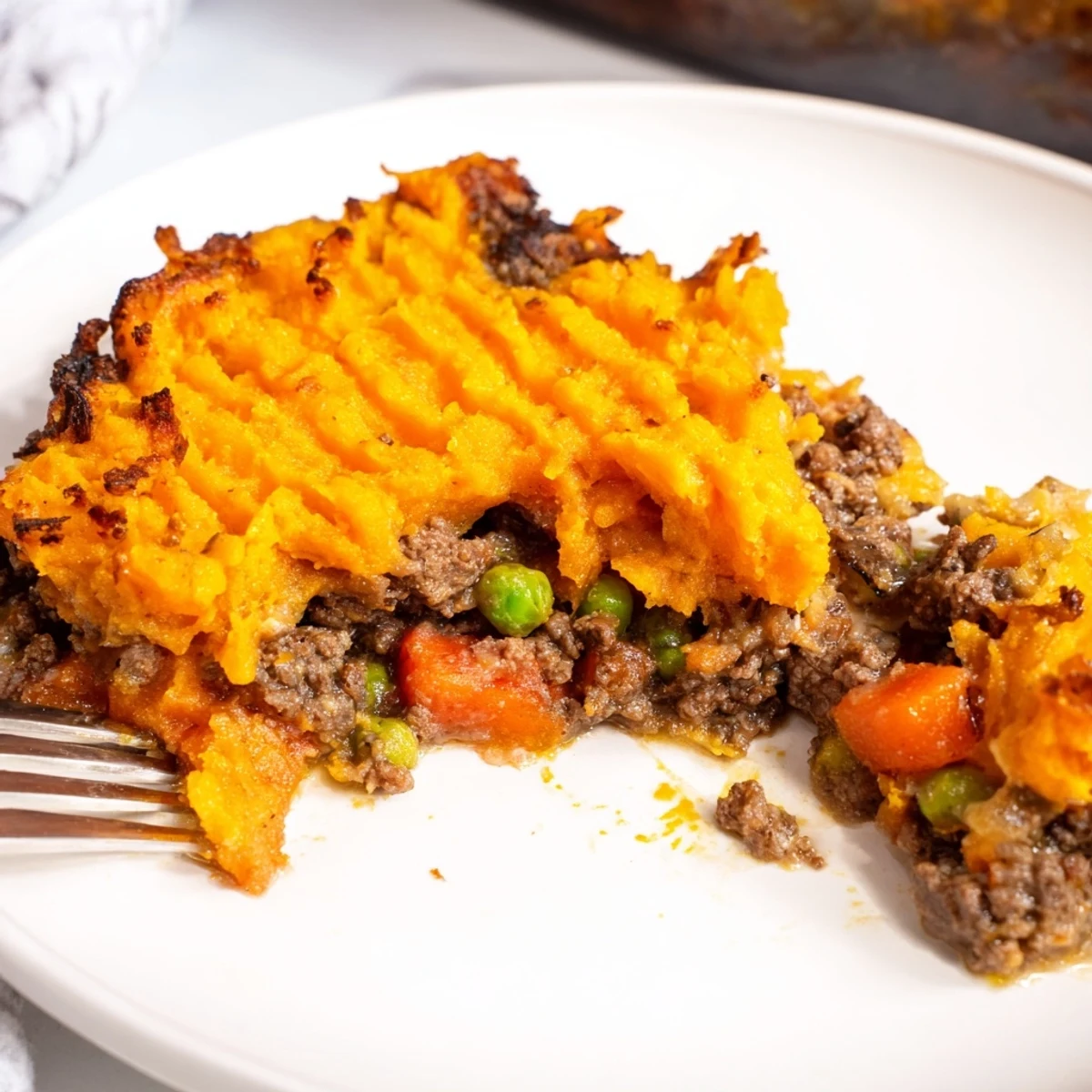 Savory ground beef, carrots, and peas bubble beneath a fork-crested layer of mashed sweet potatoes in this cozy dish.