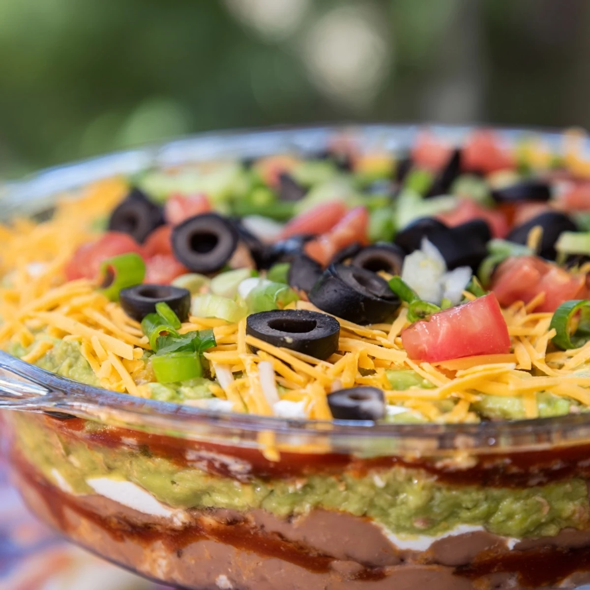 Sunlight highlights the colorful layers of refried beans, sour cream, and chunky salsa in this chilled Tex-Mex party dip, ready for dipping.