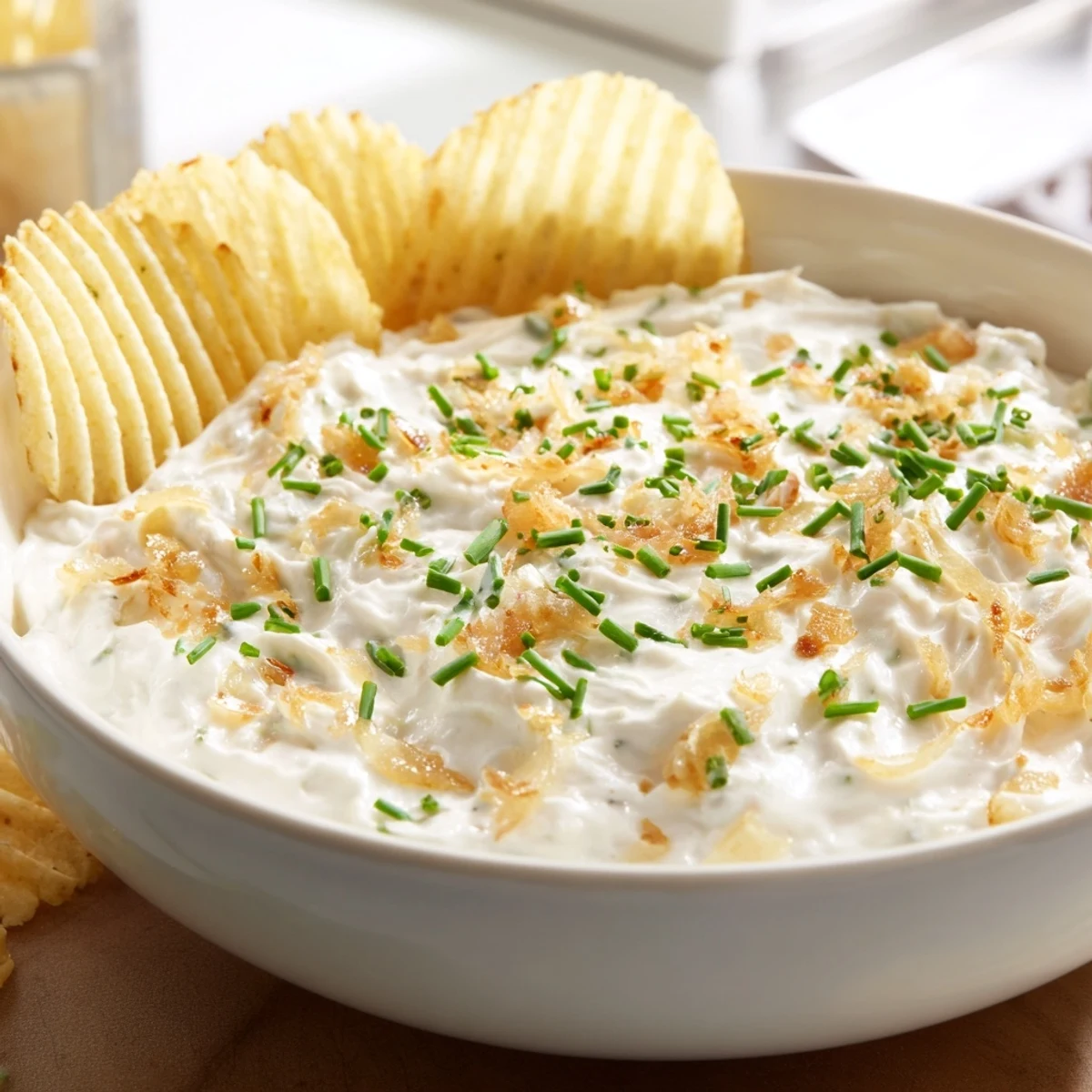 A festive platter of Game Day Onion Dip surrounded by crunchy potato chips and fresh veggies, ready for an American football party spread.