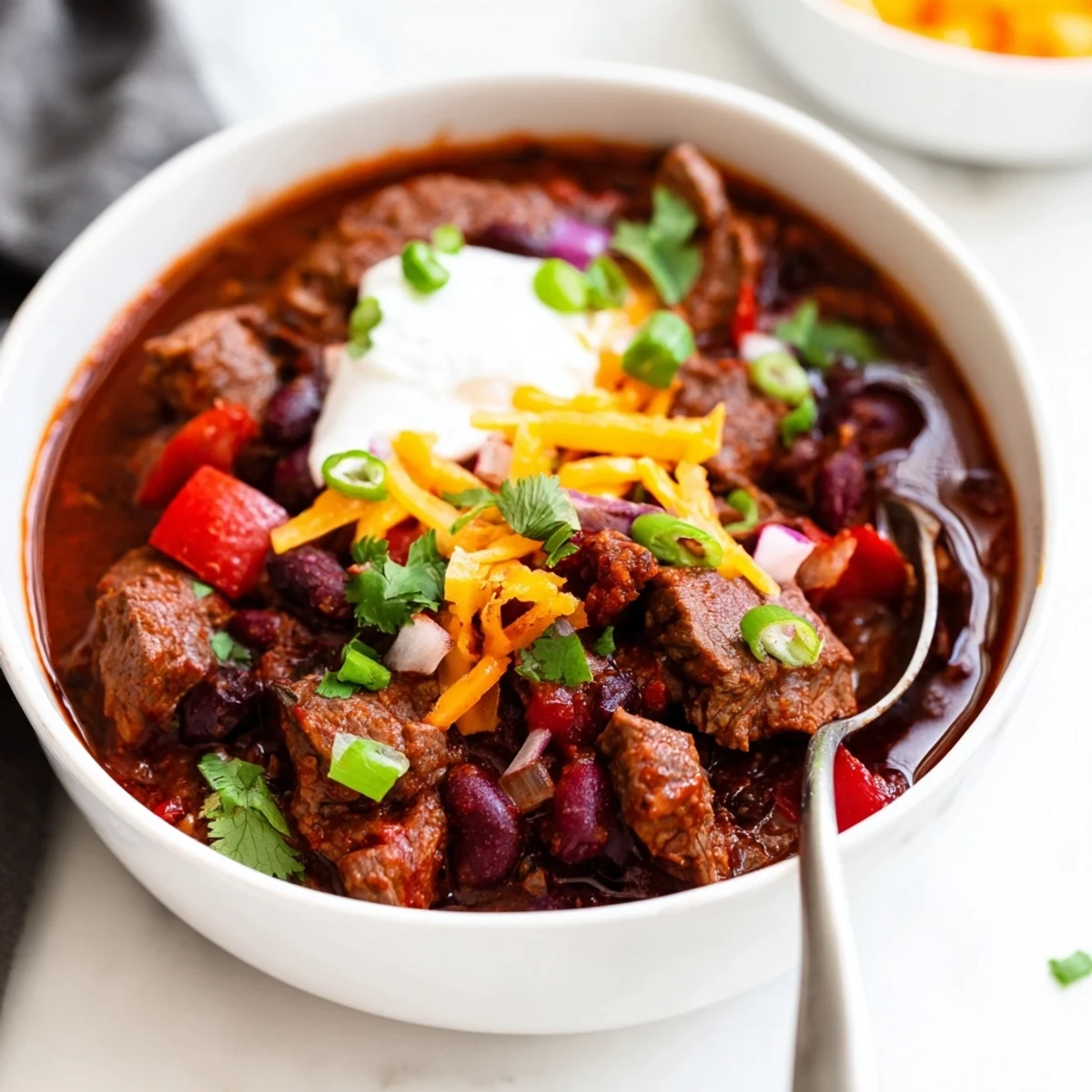 Slow Cooker Beef Chili with Beans in a slow cooker crock, bubbling with deep red sauce, kidney beans, and pieces of slow-cooked beef.