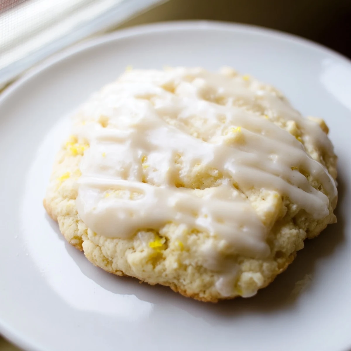 A plate of tender Lemon Ricotta Cookies drizzled with sweet glaze, paired with a glass of milk.