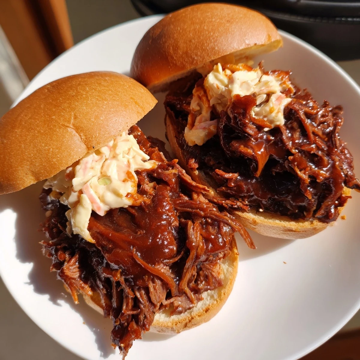 Slow-cooker Tailgate Pulled Beef Sandwiches with smoky barbecue sauce, ready to serve on soft rolls with optional crisp coleslaw topping.