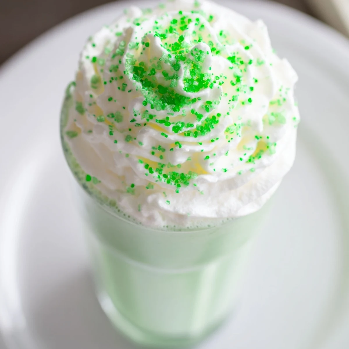 Two servings of Shamrock Mint Milkshake with a maraschino cherry garnish, ready to sip through a straw on a warm day.  