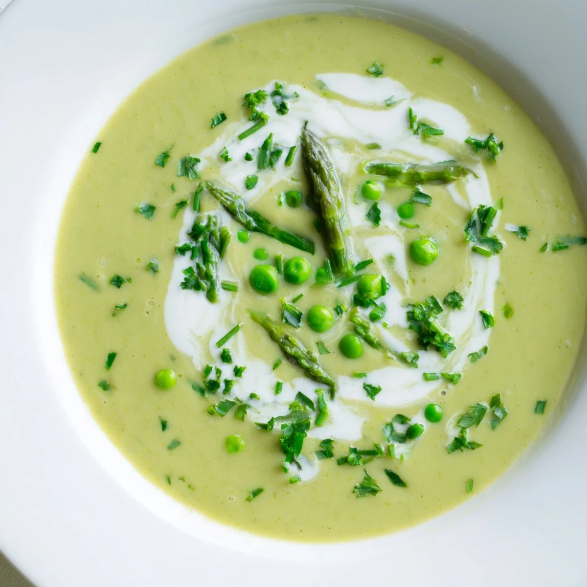 The velvety green soup features tender roasted asparagus and sweet peas, served with a crusty bread slice on the side. 