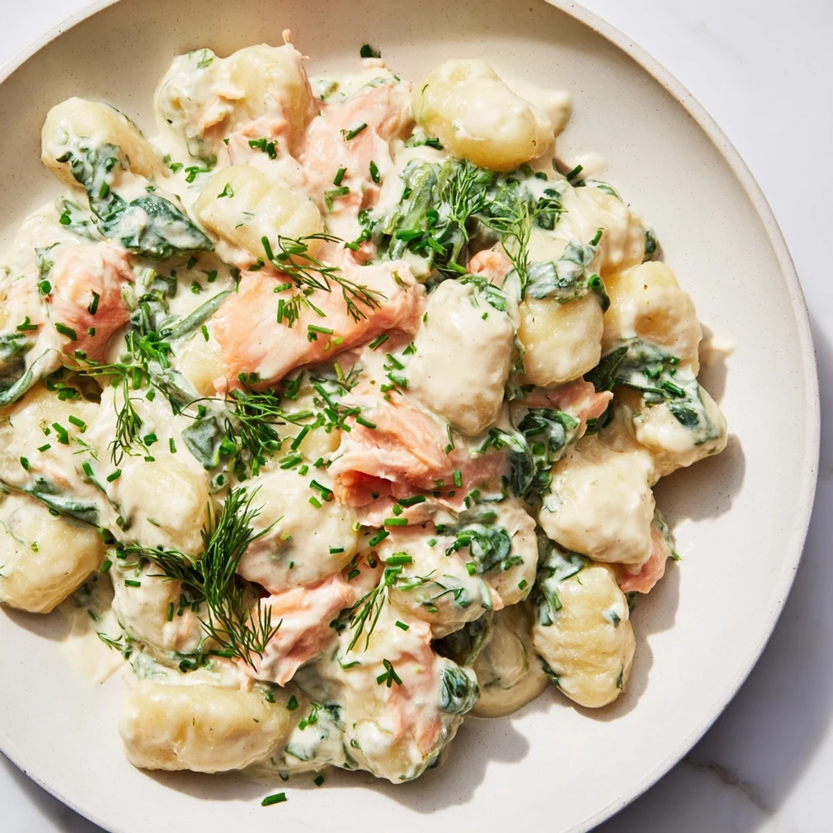 Healthy Smoked Salmon Gnocchi plated on a white dish, garnished with chives and lemon, ready for a comforting dinner.