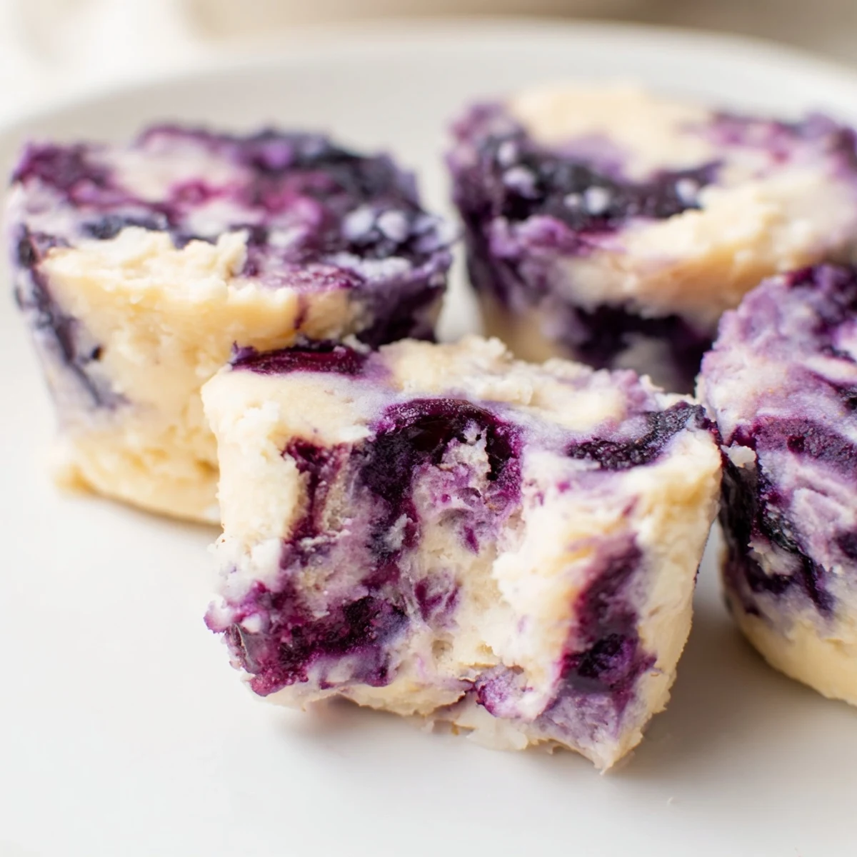 A close-up view of these Blueberry Cheesecake Protein Bites reveals a graham cracker crust base and juicy blueberries inside.  