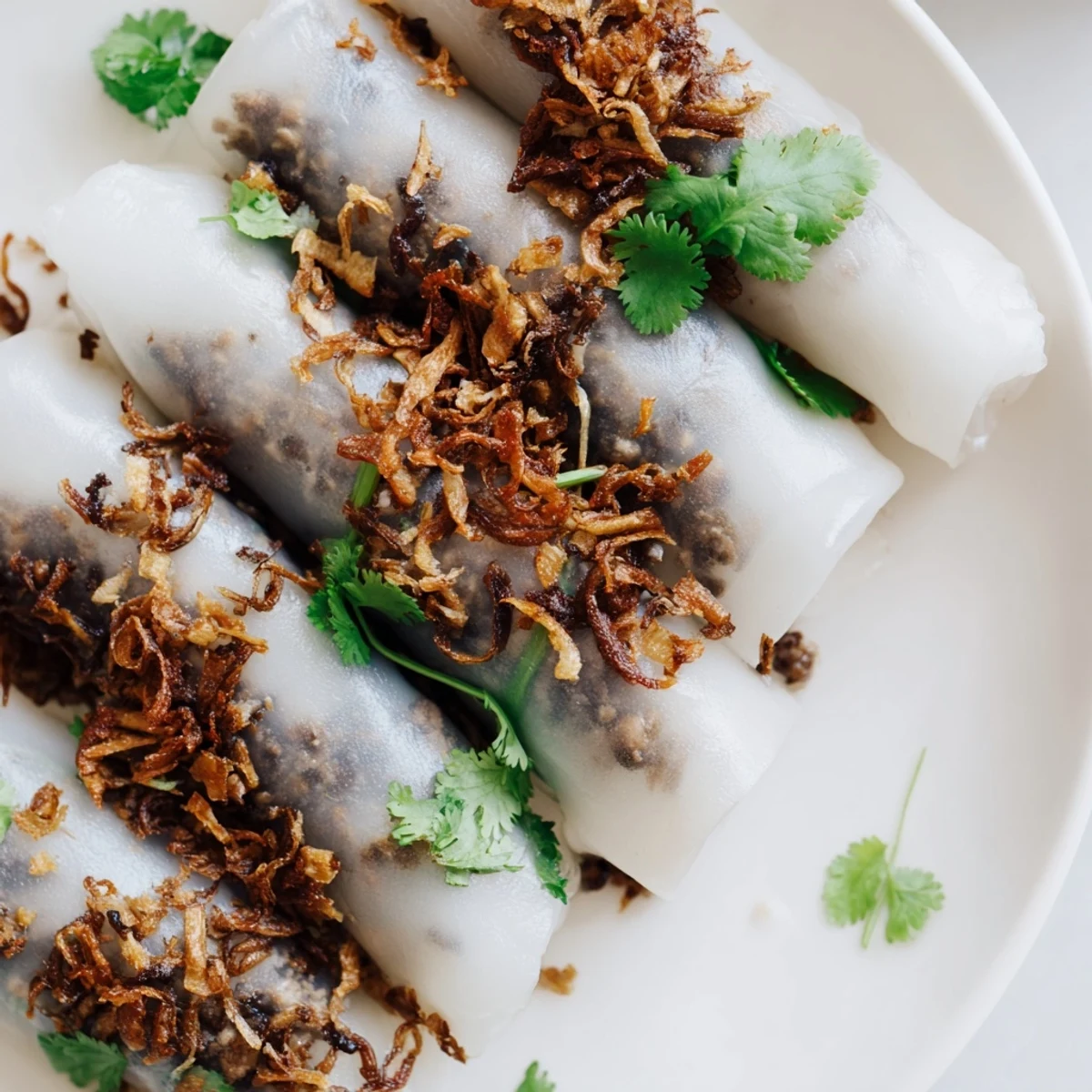Steaming Banh Cuon rice rolls release a delicate, silky texture, filled with savory pork and mushrooms on a plate.