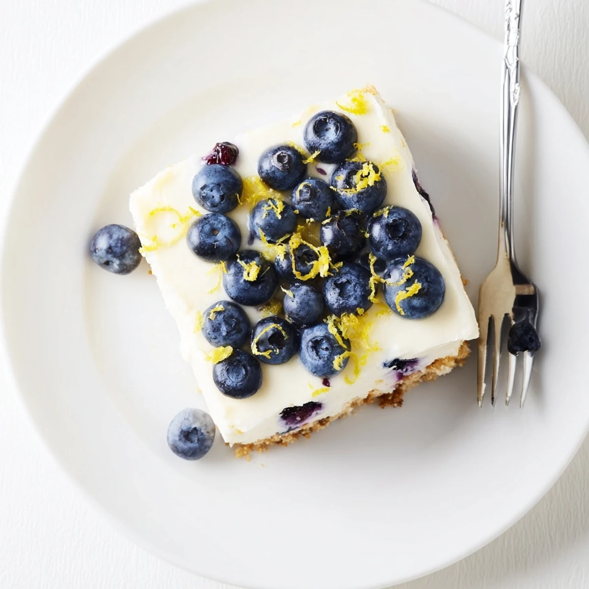 No bake lemon blueberry cream cake topped with fresh blueberries and lemon zest on a graham cracker crust