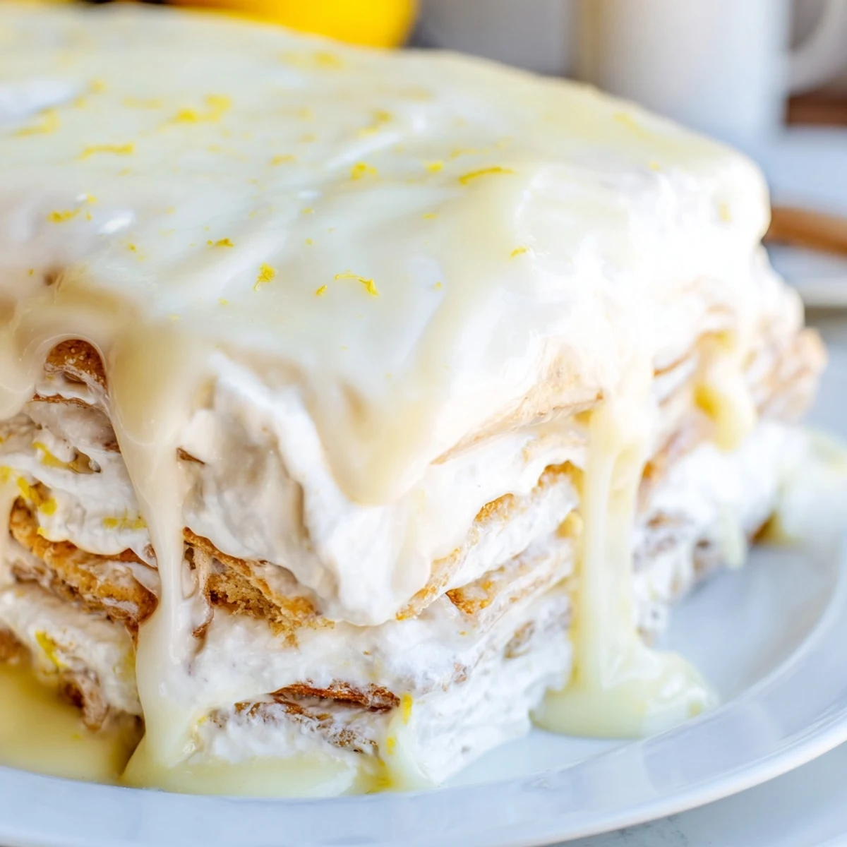 Chilled no bake lemon eclair cake square plated on white dish with zesty lemon garnish