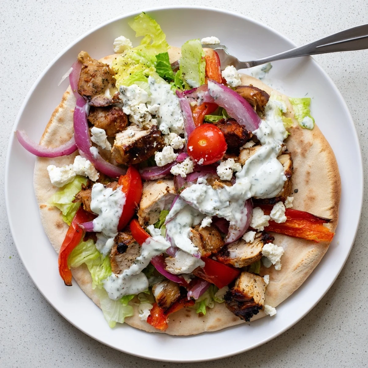 Juicy sheet pan chicken thighs with roasted red onion and bell peppers stuffed inside soft pita breads with creamy ranch sauce