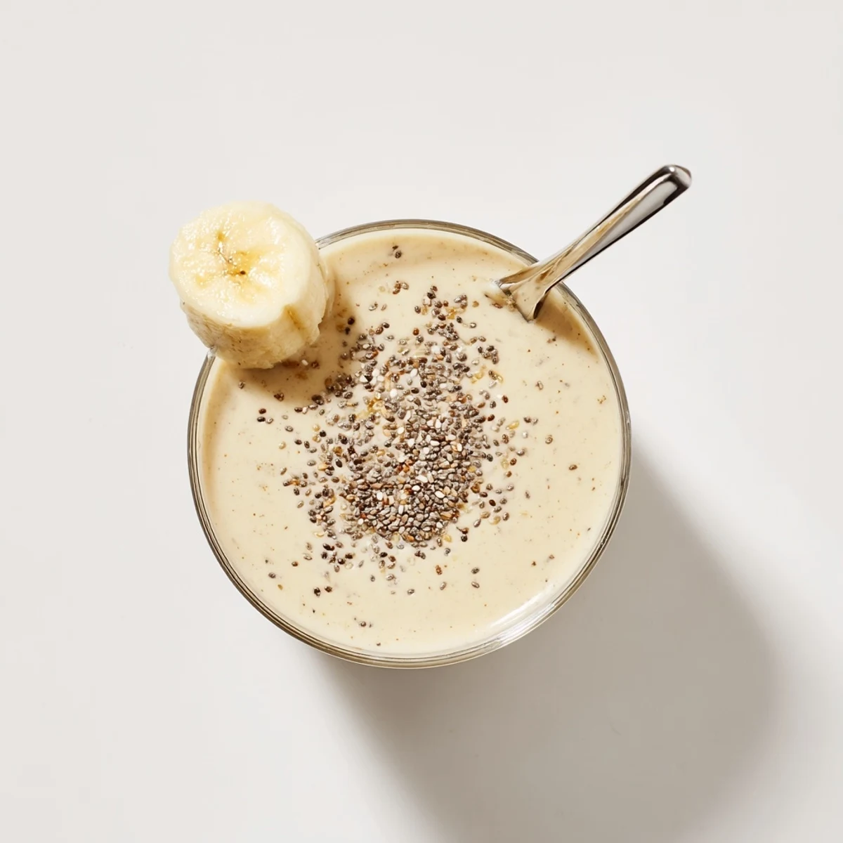 Thick healthy Greek yogurt banana smoothie topped with cinnamon and chia seeds in clear glass