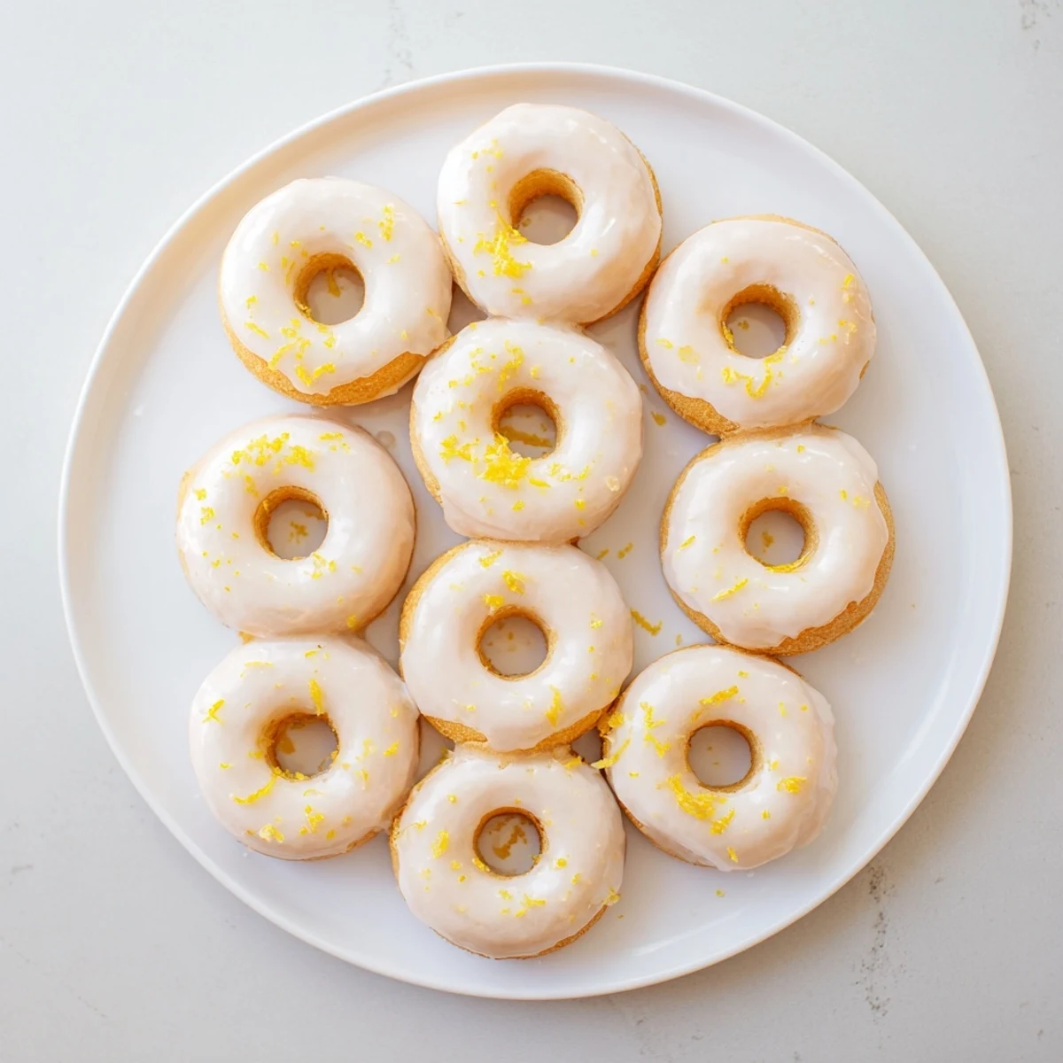 Soft chewy lemon mochi donuts arranged on a white plate with powdered sugar drizzle