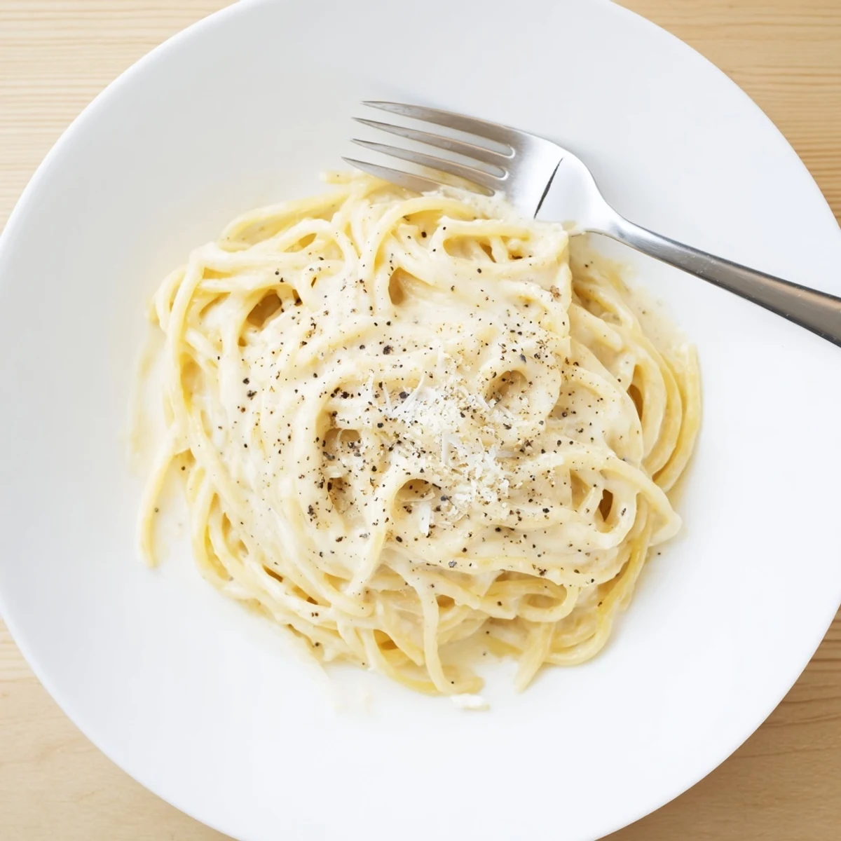 Plate of Cacio e Pepe Pasta topped with freshly ground black pepper and grated cheese