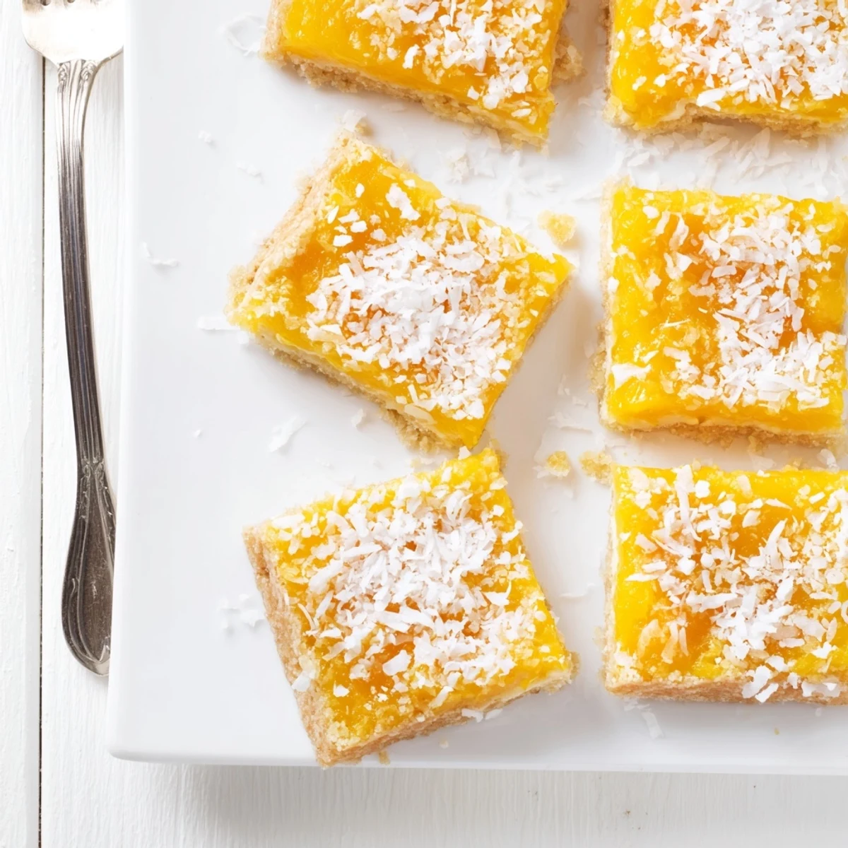 Chewy tropical mango coconut bars cut into squares on white serving plate