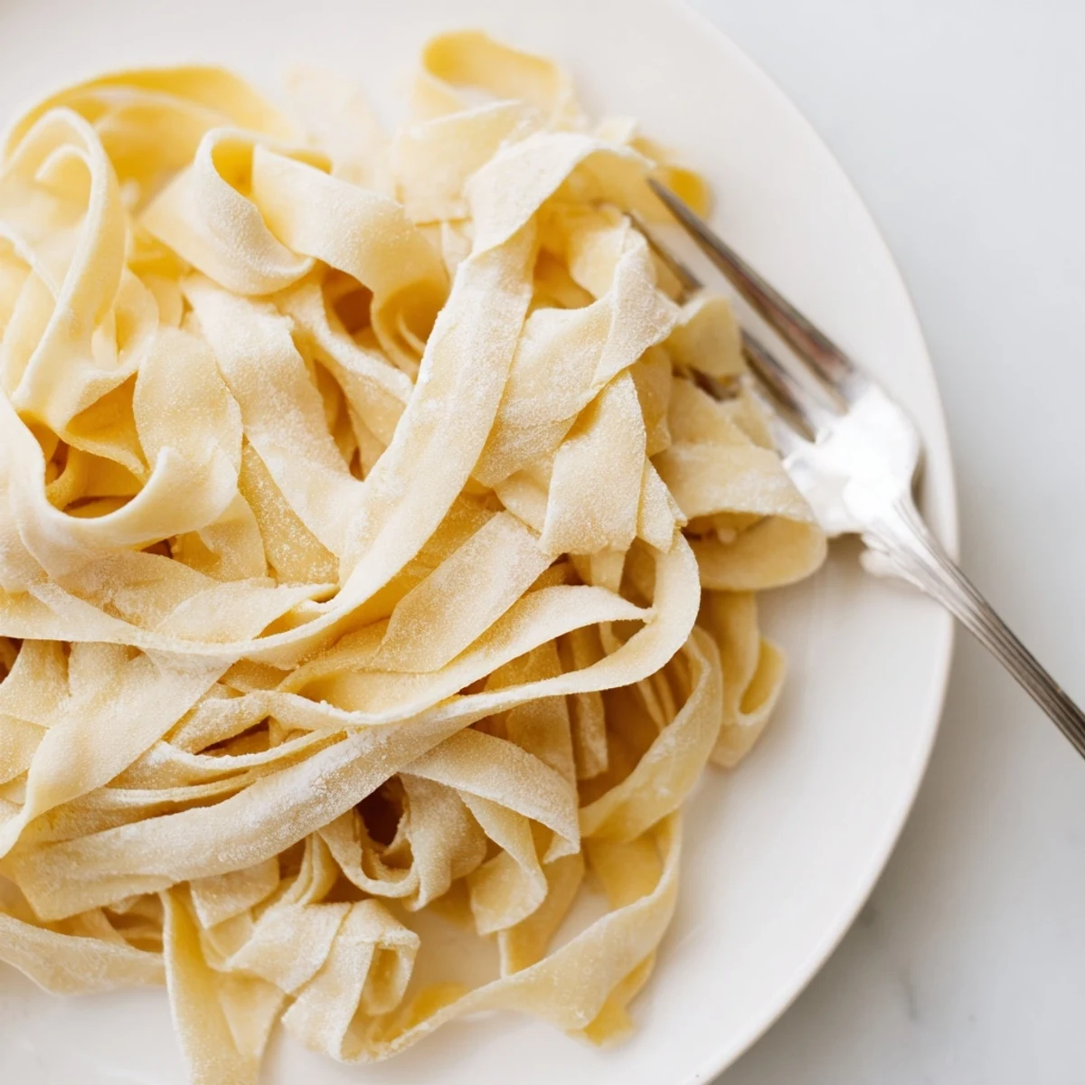 Fresh homemade sourdough pasta noodles dusted with flour on wooden cutting board
