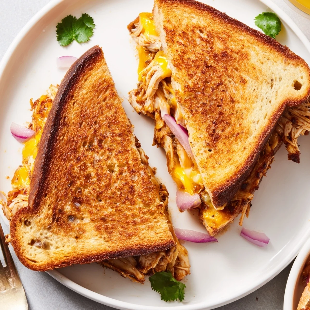Sliced BBQ chicken grilled cheese sandwich oozing melted cheese with golden brown sourdough bread exterior