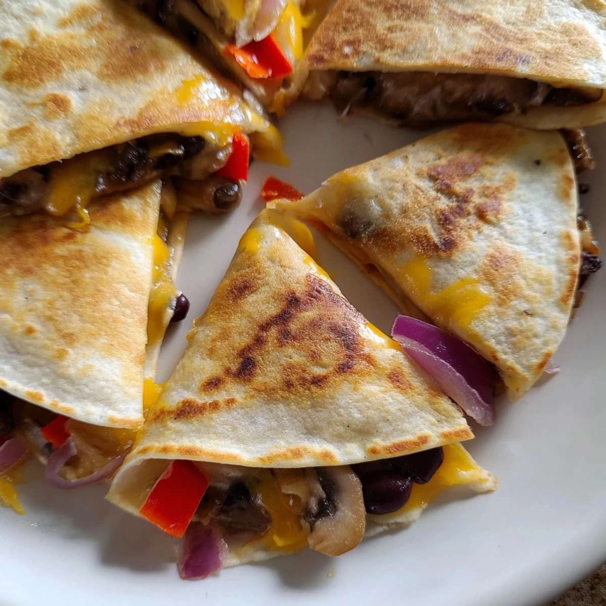 Golden brown quesadillas with melted cheddar and Monterey Jack cheese spilling from crispy tortilla wedges