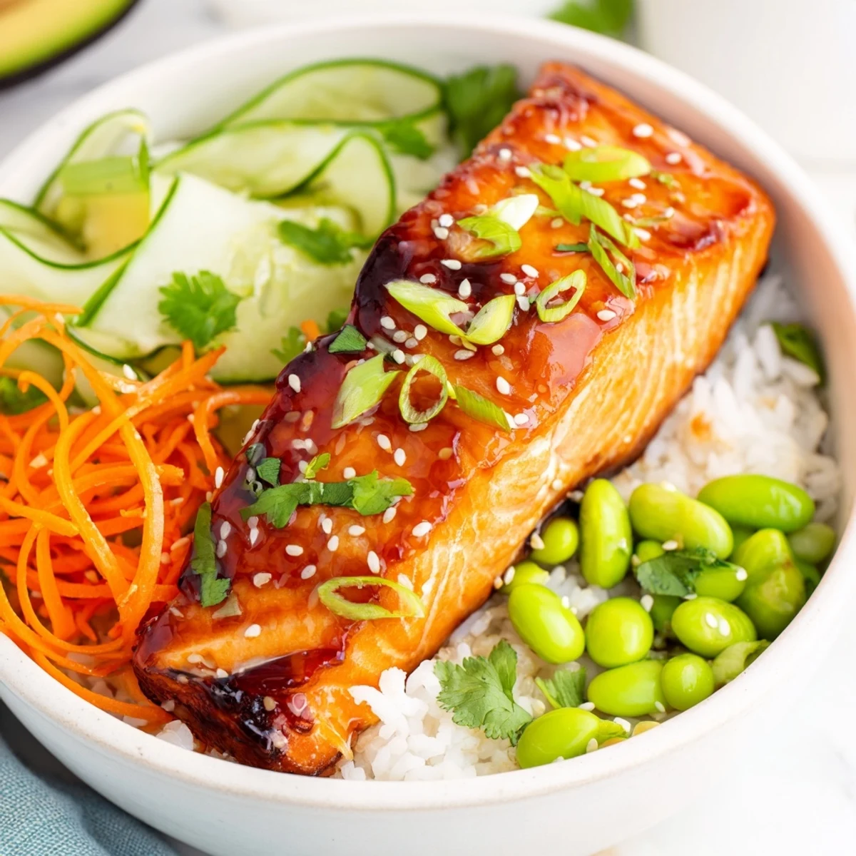 Tender honey glazed salmon fillet resting on jasmine rice alongside crisp cucumber carrot and fresh avocado slices
