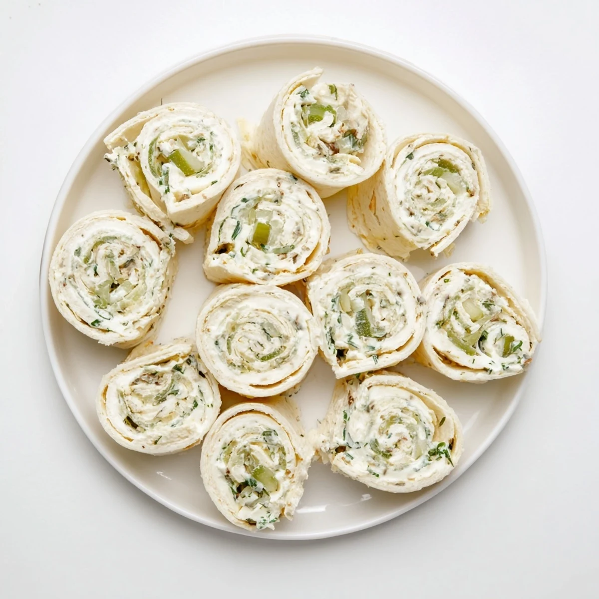 Pickle dip pinwheels featuring creamy dill filling rolled in soft flour tortillas, sliced into colorful spirals on a serving platter.