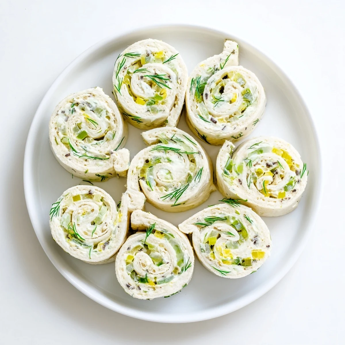Tortilla spirals stuffed with tangy cream cheese and chopped dill pickles, arranged as bite-sized appetizer pinwheels for easy party snacking.