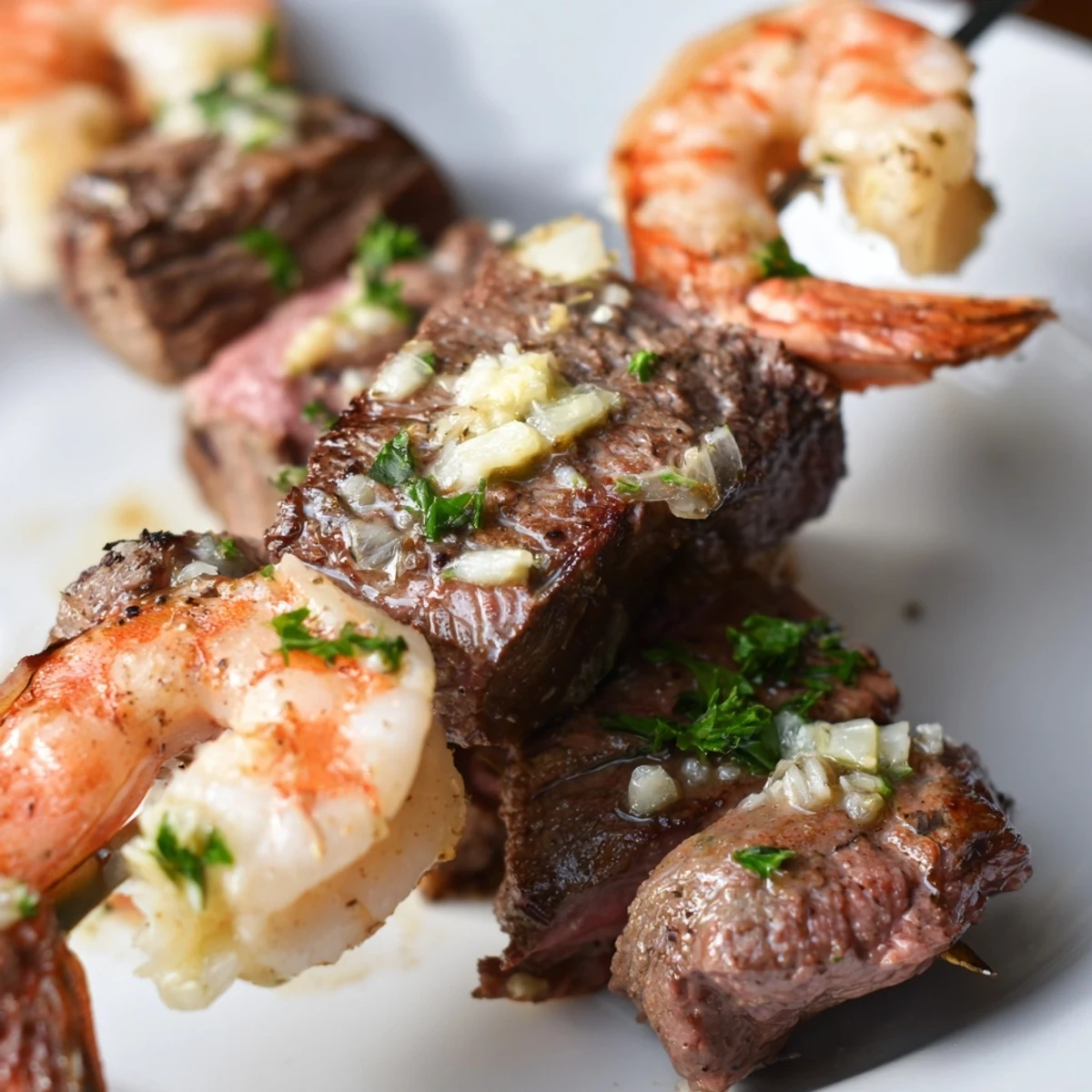 Grilled steak and shrimp skewers drizzled with rich garlic butter sauce on a wooden platter