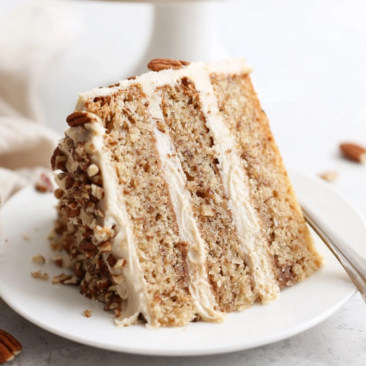 Decadent three-layer butter pecan cake with smooth frosting and pecan halves on rustic surface
