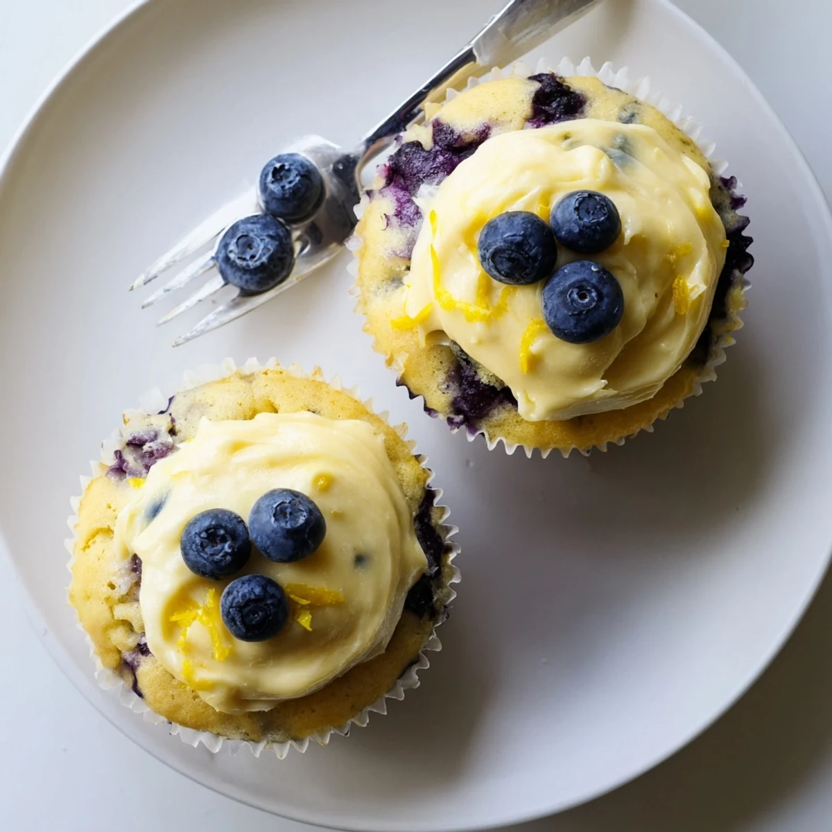 Golden lemon blueberry cupcakes topped with creamy lemon frosting and fresh berry garnish