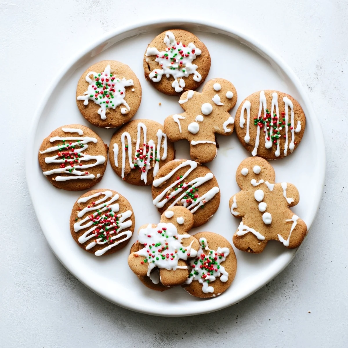 Freshly baked classic gingerbread men cookies topped with white icing swirls and red green sprinkles.