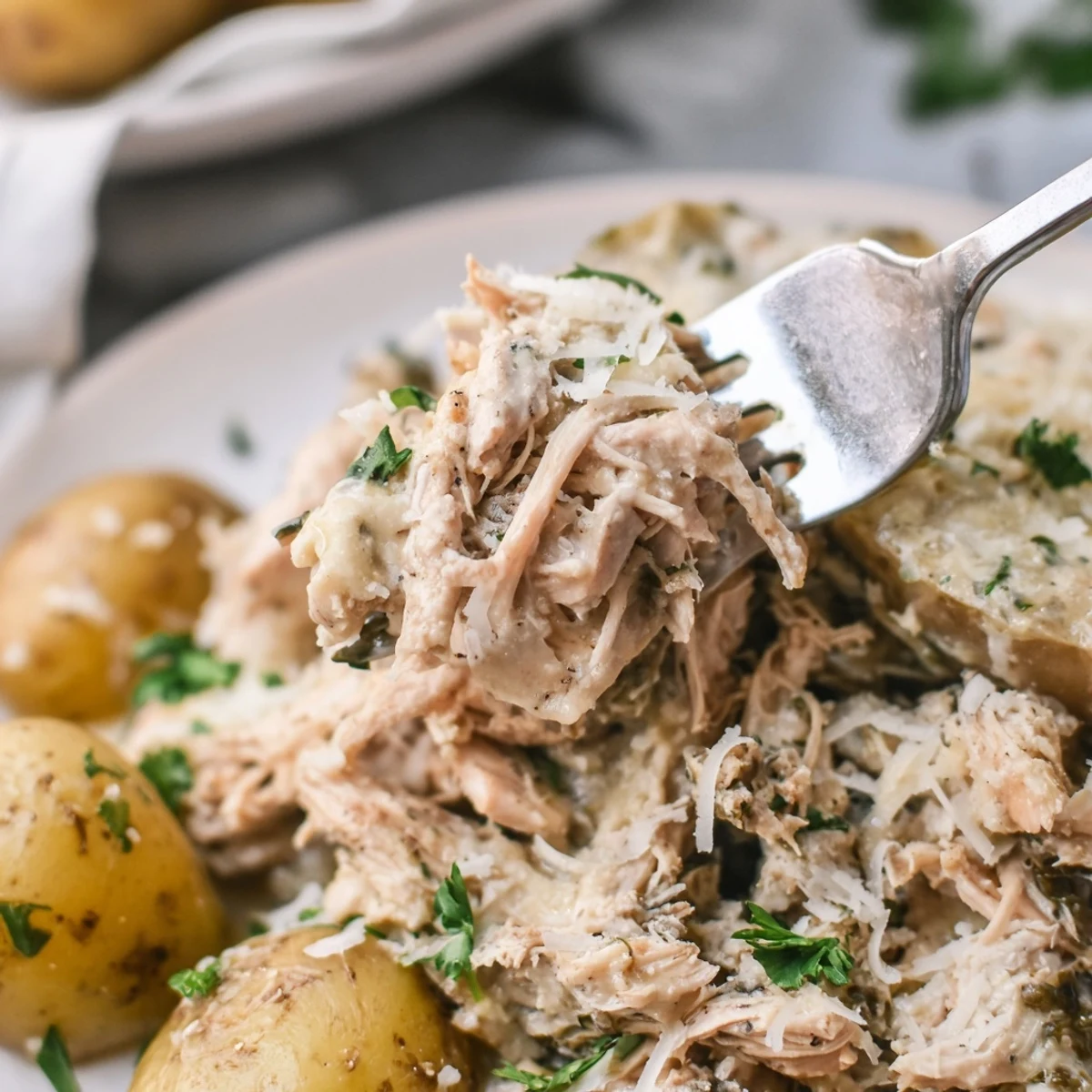 Creamy garlic parmesan chicken and potatoes slow cooked to perfection with fresh parsley garnish