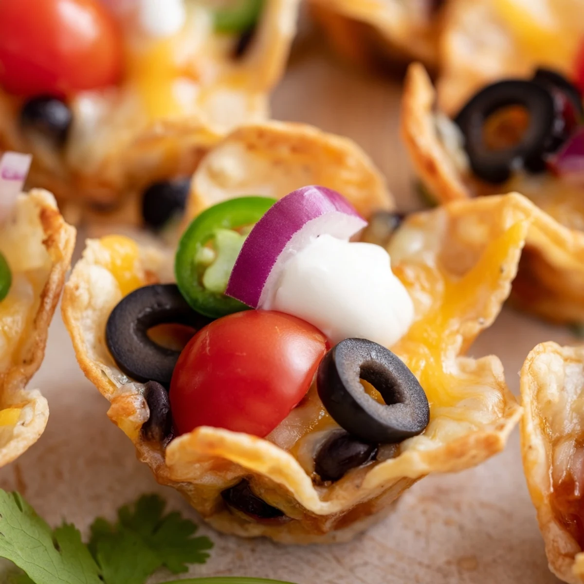 Golden cheesy nacho cups bubbling with melted cheddar and colorful fresh toppings arranged on a platter