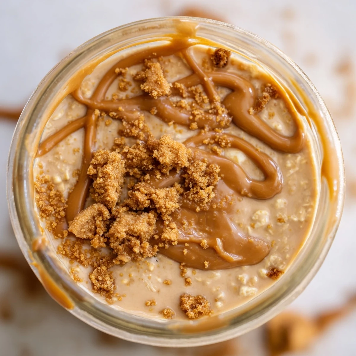 Creamy quick Biscoff overnight oats topped with crushed cookies in a glass jar
