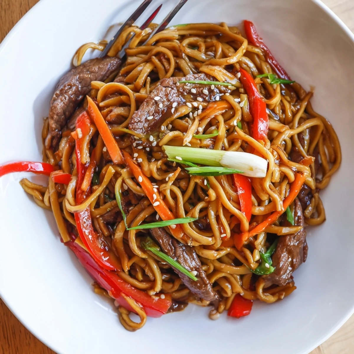 Weeknight Sticky Beef Noodles glistening in sweet-savory sauce, served with chopsticks
