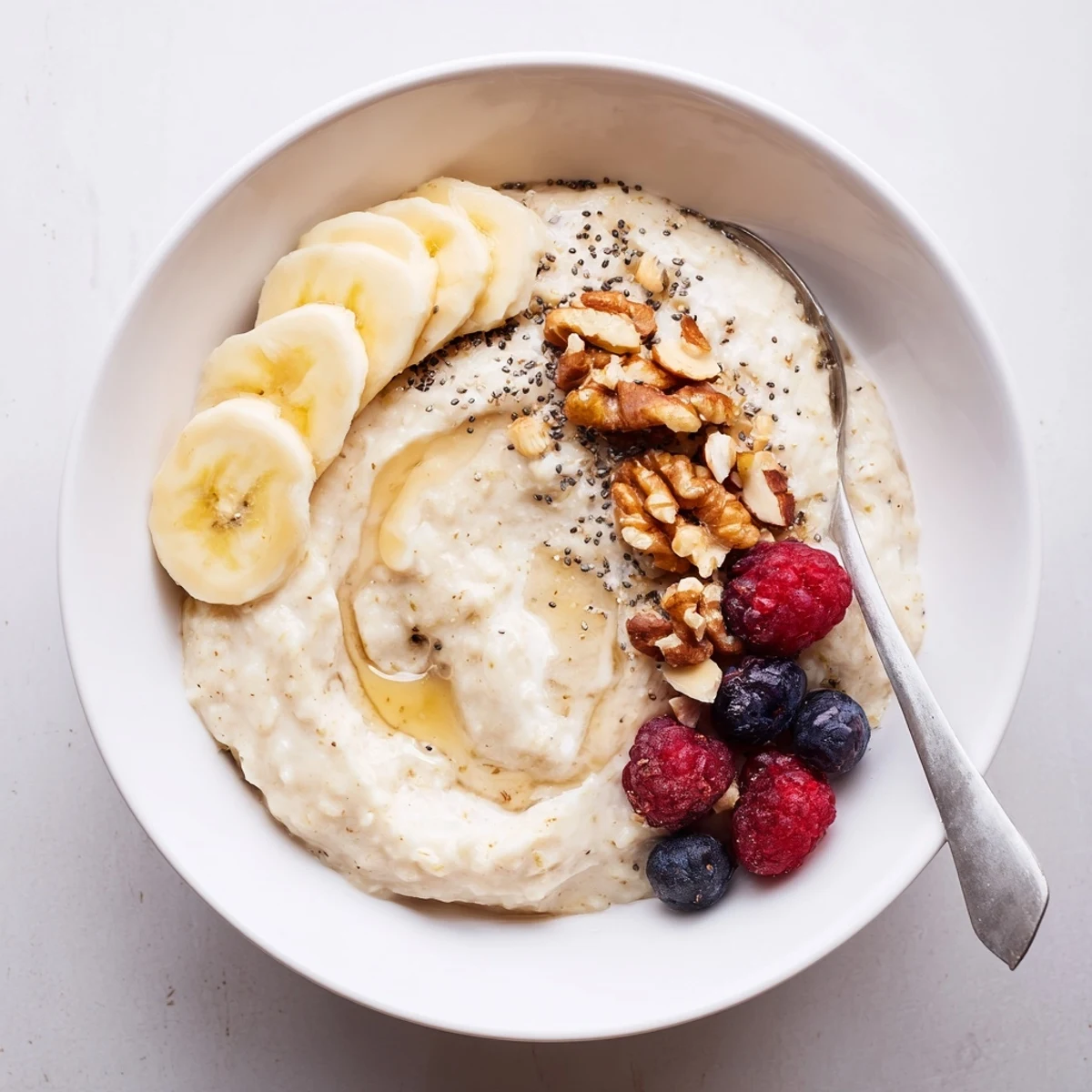 Protein Oatmeal topped with banana, nuts, and fresh berries, steaming