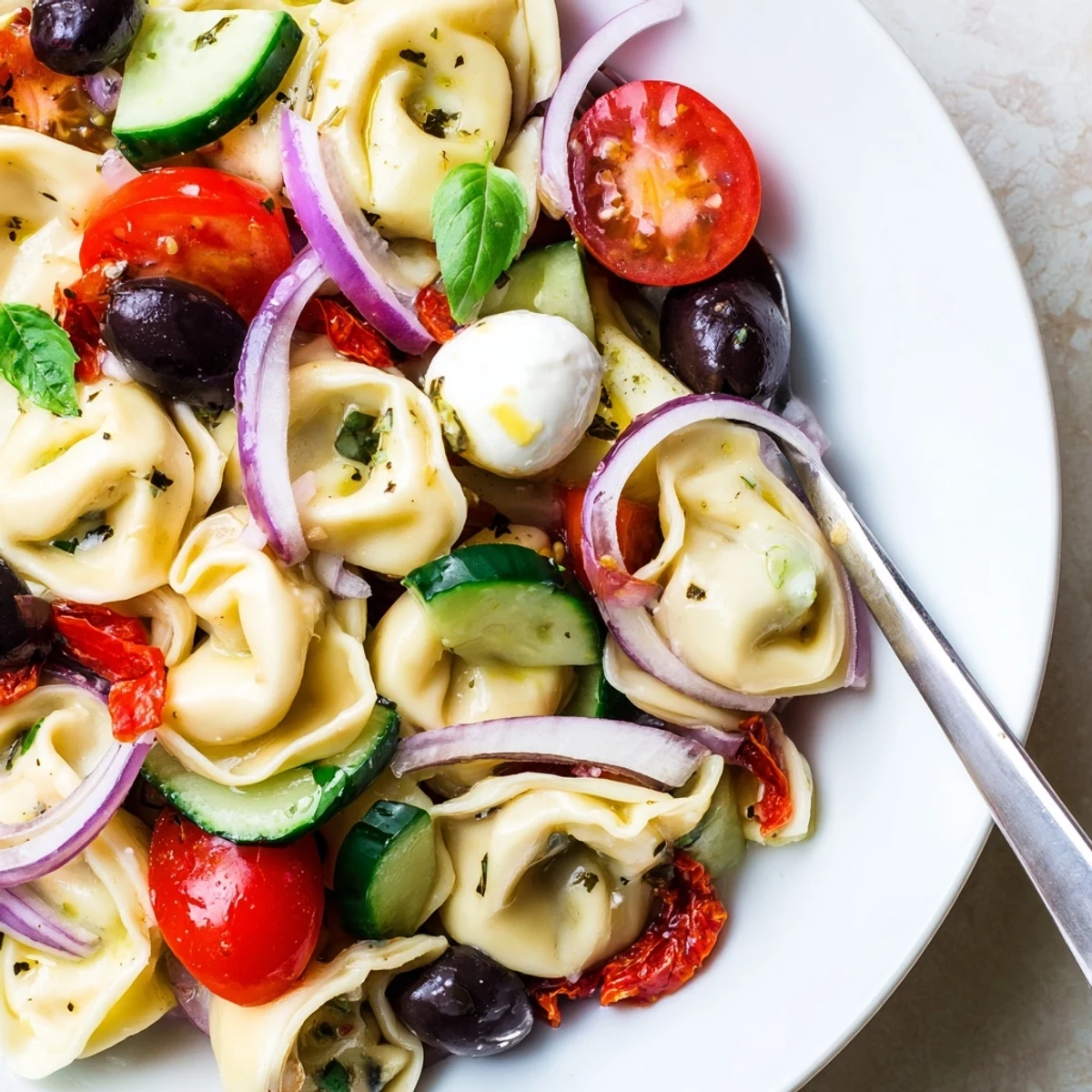 Tortellini Pasta Salad with glossy tomatoes, fresh basil, chilled for a picnic.