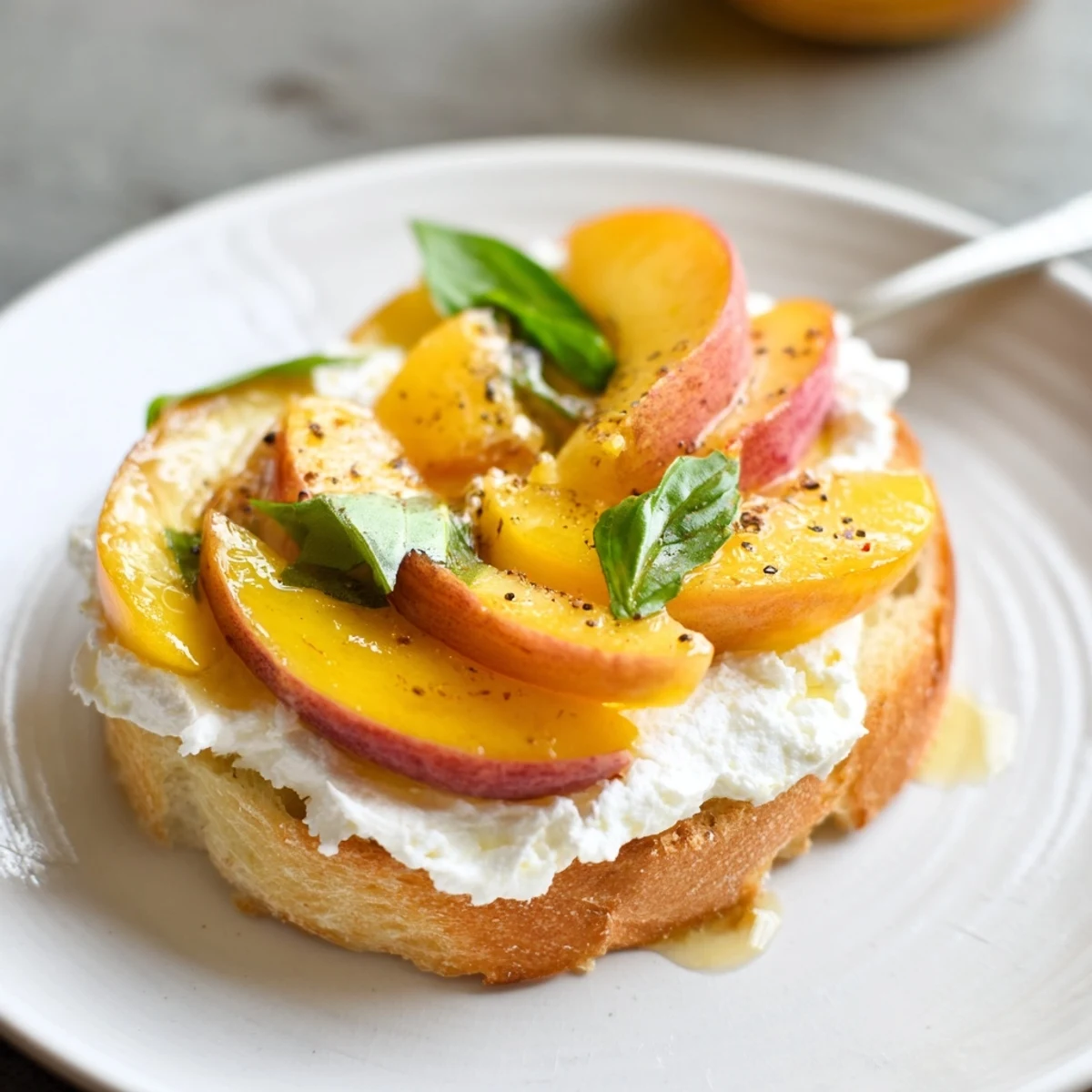Bright Peach Bruschetta With Whipped Ricotta topped with cracked pepper and sea salt.