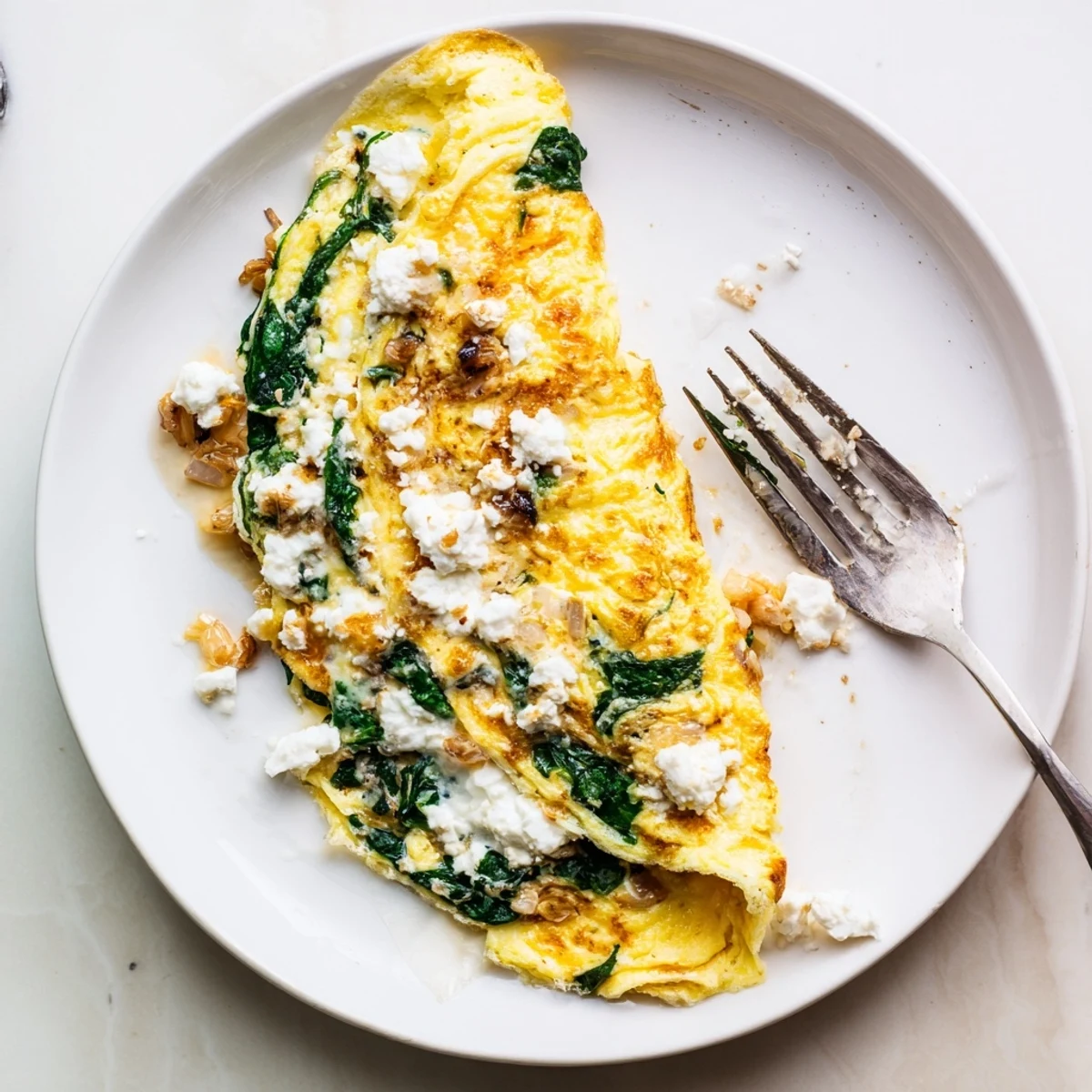 Fluffy Mediterranean omelet filled with wilted spinach and creamy feta cheese close-up