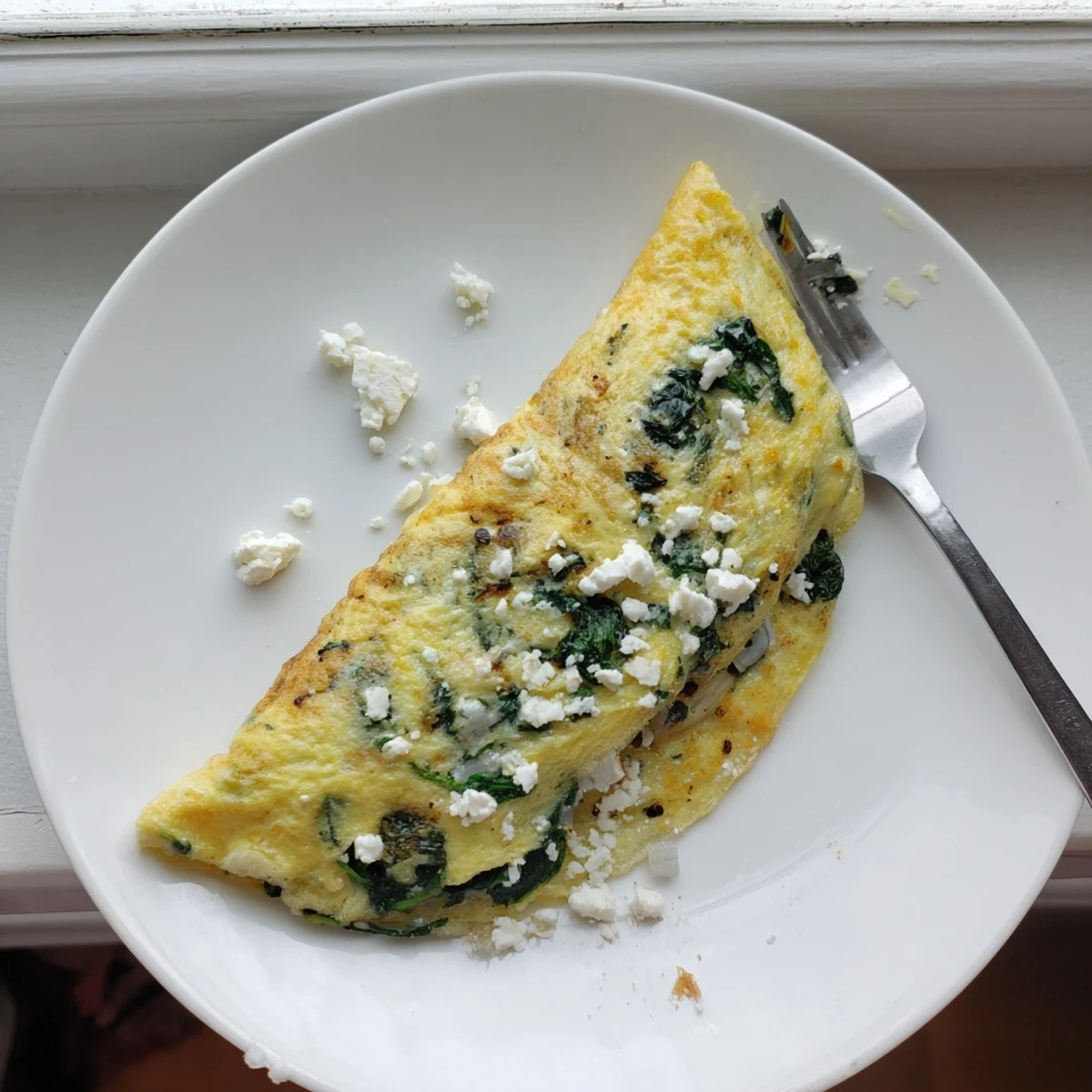 Savory breakfast omelet with tender spinach leaves and melted feta cheese halves