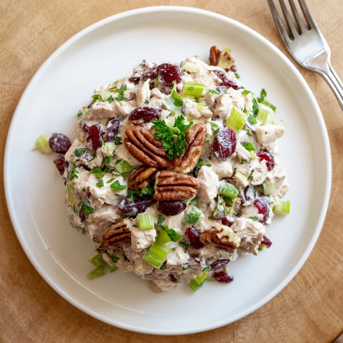 Creamy cranberry pecan chicken salad served in a white bowl with scattered toasted pecans and vibrant red cranberries on top.