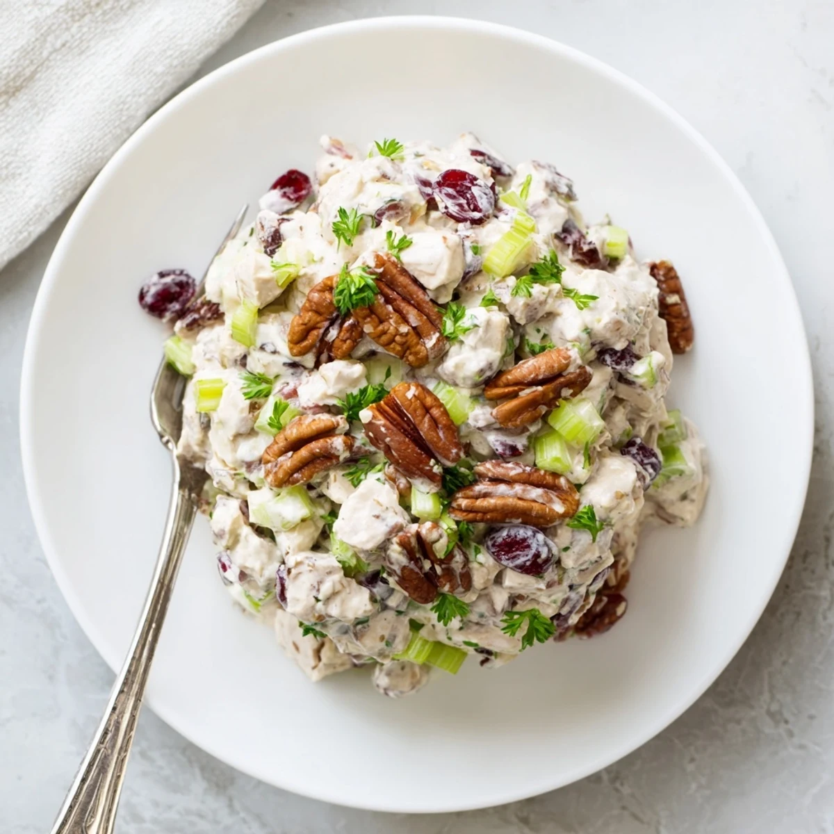 Fresh chicken salad with tart dried cranberries and crunchy pecans ready for scooping onto croissants or crisp lettuce cups.