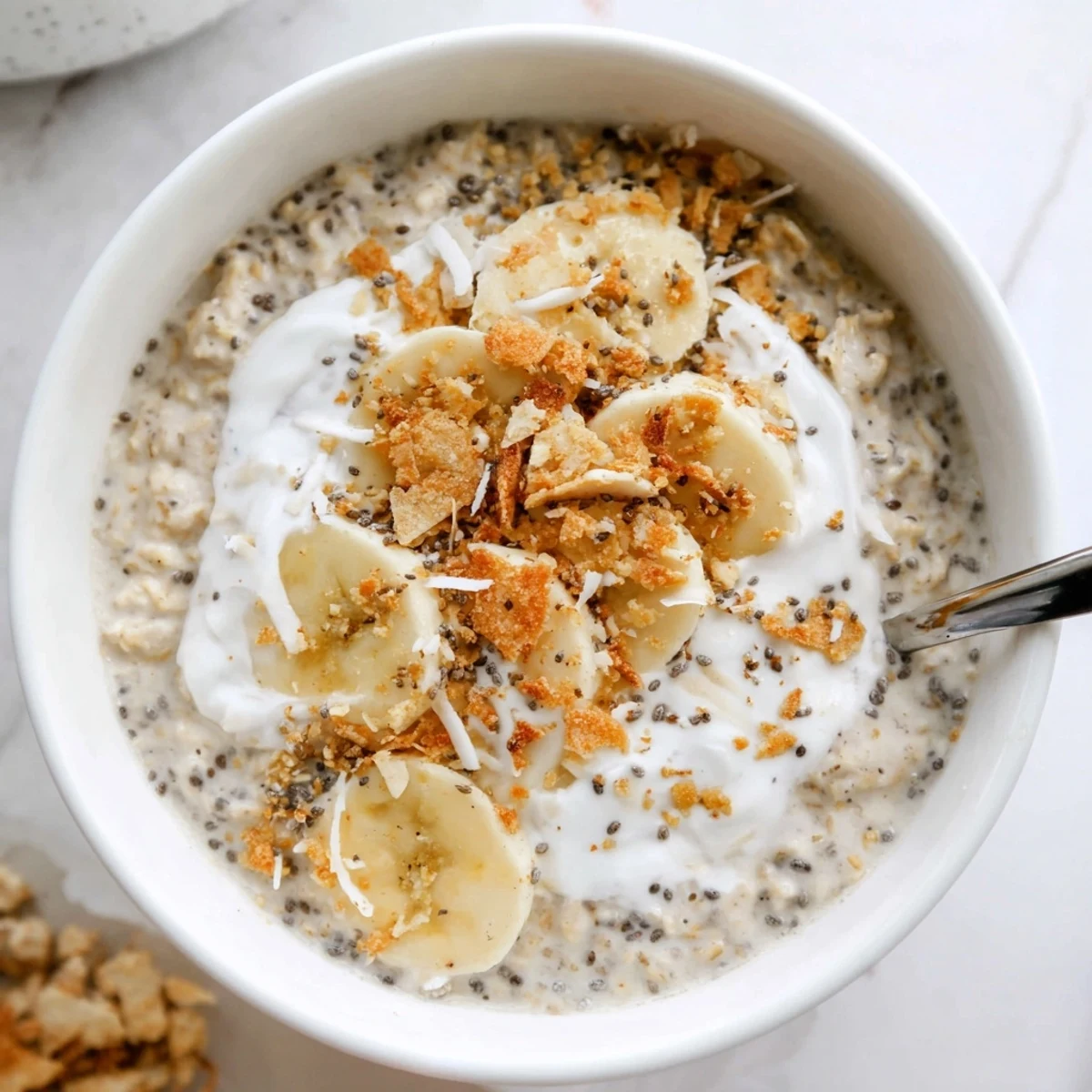 Creamy Coconut Cream Pie Overnight Oats topped with toasted coconut and banana