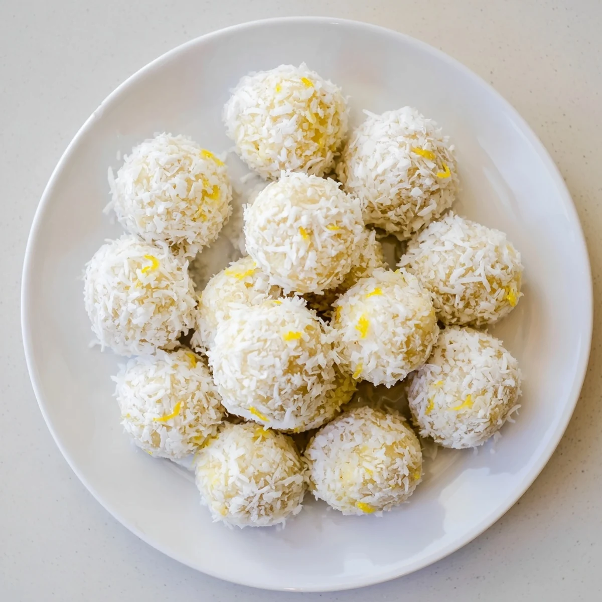 Golden Citrus Bliss Bites rolled in coconut, perfect refreshing baby shower dessert on white plate