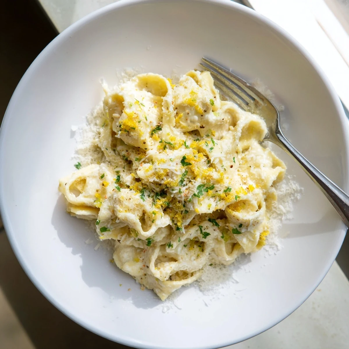 Comforting creamy cafeteria noodles in a white bowl topped with fresh green parsley and grated Parmesan