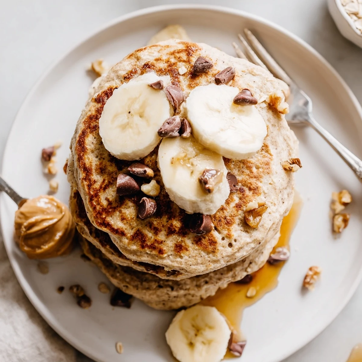 Protein Banana Pancakes stacked, steam rising, topped with maple syrup and nuts