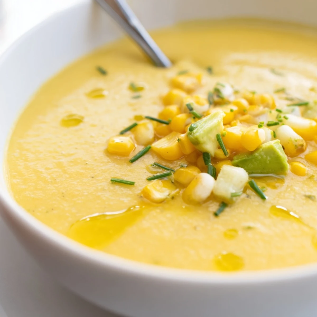 Creamy Summer Sweet Corn Gazpacho garnished with raw corn kernels cilantro and diced ripe avocado