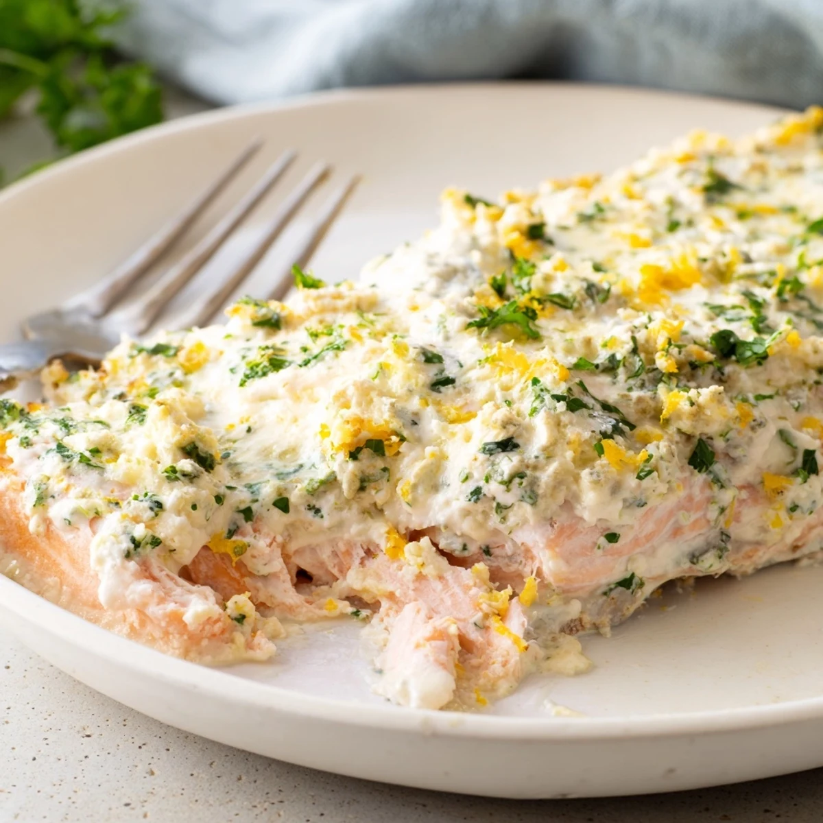 Boursin salmon topped with melted herb cheese served on a white plate