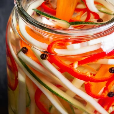 A close-up of the Vietnamese Vegetable Pickle Medley with colorful bell pepper and cucumber slices, ready for a banh mi sandwich.