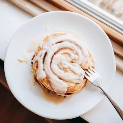 Fluffy pancakes swirled with cinnamon sugar filling, served warm with creamy glaze.