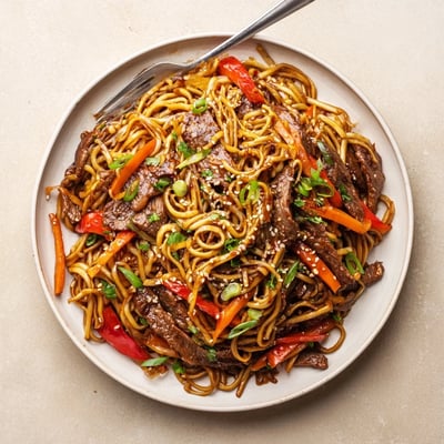 Plate of Sticky Beef Noodles with tender beef strips and crunchy vegetables